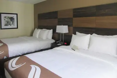 a hotel room with two beds and a lamp at Quality Inn and Conference Center in Richmond