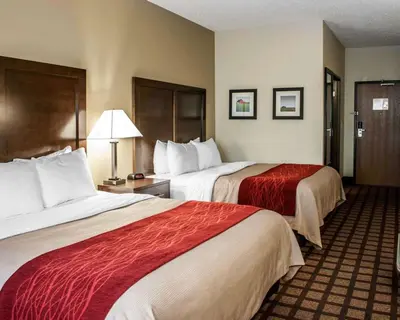 a hotel room with two beds with red sheets at Baymont by Wyndham Richmond I-70 in Richmond