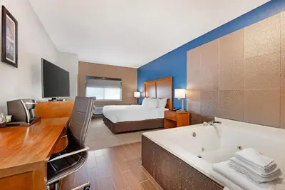 a hotel room with a tub and a bed at Comfort Inn & Suites North Greenfield in Greenfield