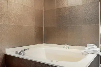 a bathroom with a tub with a mirror and towels at Comfort Inn & Suites North Greenfield in Greenfield