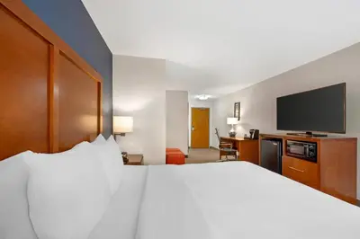 a hotel room with a bed and a flat screen tv at Comfort Inn & Suites North Greenfield in Greenfield