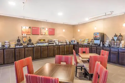 a fast food restaurant with tables and red chairs at Comfort Suites Fort Wayne North in Fort Wayne