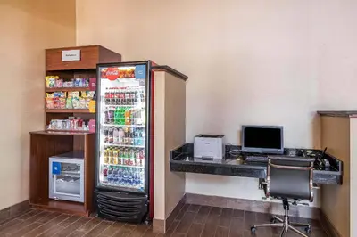 a refrigerator in a room with a desk and a computer at Comfort Suites Fort Wayne North in Fort Wayne