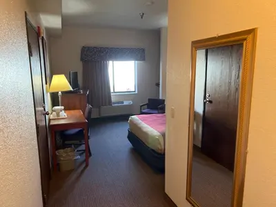 a hotel room with a bed and a desk and a mirror at Express Inn & suites in Decatur