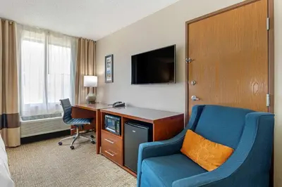 a hotel room with a desk and a blue chair at Comfort Inn Anderson South in Anderson