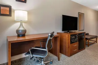 a room with a desk with a television and a chair at Comfort Inn & Suites Lawrenceburg in Lawrenceburg