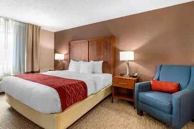 a hotel room with a bed and a blue chair at Comfort Inn & Suites Lawrenceburg in Lawrenceburg