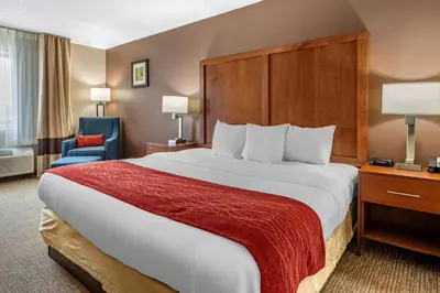 a hotel room with a large bed with a red blanket at Comfort Inn & Suites Lawrenceburg in Lawrenceburg