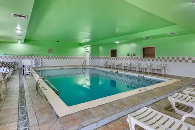 a large swimming pool with white chairs and tables at Comfort Inn & Suites Lawrenceburg in Lawrenceburg