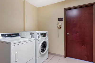 a laundry room with a washing machine and a red door at Comfort Inn & Suites Muncie Near University in Muncie