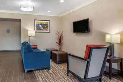 a living room with a tv and a blue chair at Comfort Inn & Suites Muncie Near University in Muncie