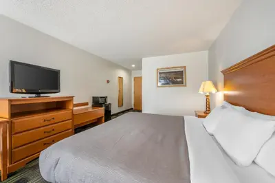 a hotel room with a bed and a flat screen tv at Quality Inn & Suites Near Amish Country in Rushville