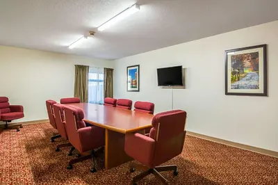 a conference room with a wooden table and red chairs at Quality Inn & Suites Greensburg I-74 in Greensburg