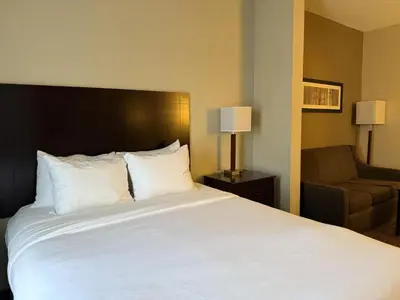 a bedroom with a large white bed and a chair at SureStay by Best Western Marion in Marion