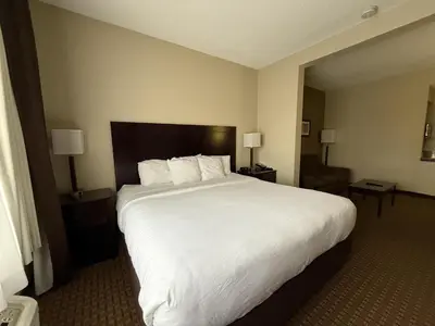 a hotel room with a large white bed and a chair at SureStay by Best Western Marion in Marion