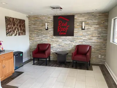 a waiting room with two red chairs and a red roof inn sign at Red Roof Inn Walton, KY - Richwood - Cincinnati Airport South in Richwood