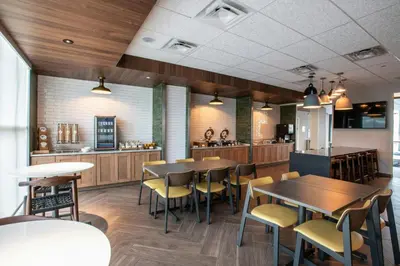a restaurant with tables and chairs and a kitchen at Fairfield by Marriott Inn & Suites Newport Cincinnati in Newport