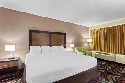 a hotel room with a large bed and a chair at Americas Best Value Inn Grayson in Grayson