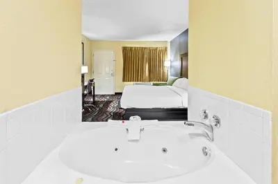 a bathroom with a sink and a bed in a room at Americas Best Value Inn Grayson in Grayson