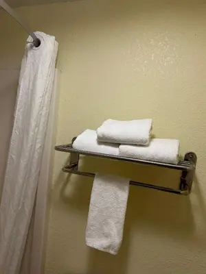 a bathroom with towels on a shelf and a shower at Americas Best Value Inn Grayson in Grayson