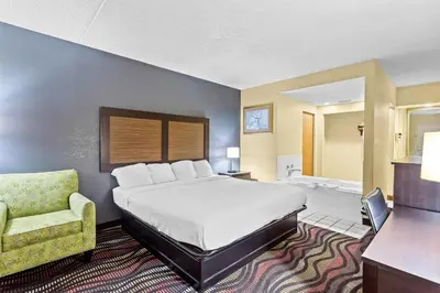 a hotel room with a bed and a chair at Americas Best Value Inn Grayson in Grayson