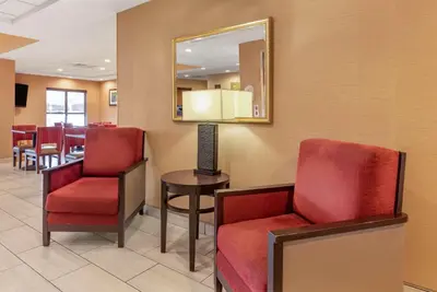 a waiting room with red chairs and a mirror at Comfort Inn & Suites Morehead in Morehead
