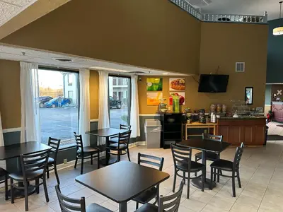 a restaurant with tables and chairs and a kitchen at Quality Inn Ashland in Ashland