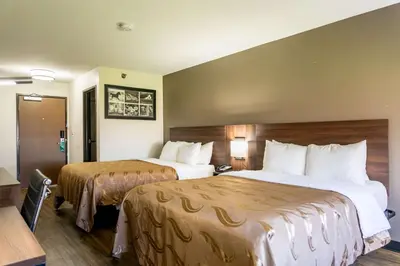 a hotel room with two beds and a desk at Quality Inn Carrollton in Carrollton