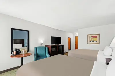 a hotel room with two beds and a chair at Quality Inn Dry Ridge in Dry Ridge