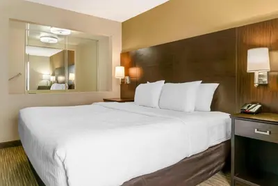 a large white bed in a hotel room with a mirror at Quality Inn & Suites Monroe in Monroe