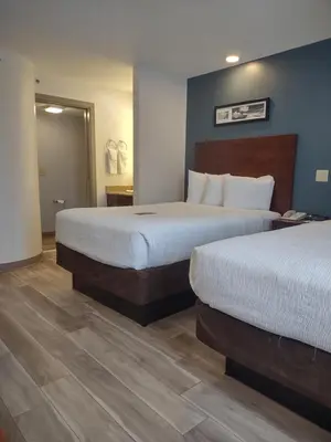 a hotel room with two beds and a bathroom at Baymont by Wyndham Flat Rock in Flat Rock