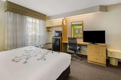 a hotel room with a bed and a desk with a television at Sleep Inn Bolivar in Bolivar