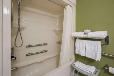 a bathroom with a shower and a toilet and towels at Sleep Inn Bolivar in Bolivar