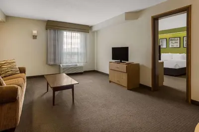 a hotel room with a couch and a tv and a bed at Sleep Inn Bolivar in Bolivar