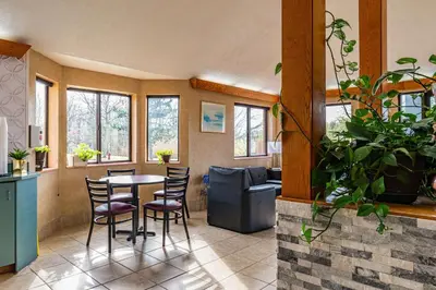 a living room with a table and chairs and windows at Econo Lodge Cleveland Southeast - Kent in Streetsboro