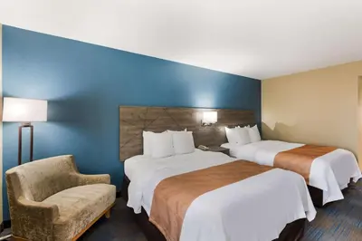 a hotel room with two beds and a chair at Quality Inn Upper Sandusky in Upper Sandusky