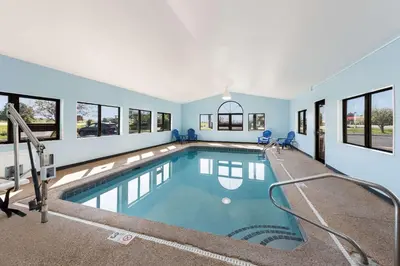 a large indoor swimming pool with blue walls and windows at Quality Inn Upper Sandusky in Upper Sandusky