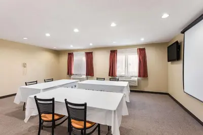 a conference room with white tables and chairs and a screen at Quality Inn Upper Sandusky in Upper Sandusky