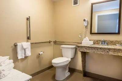 a bathroom with a toilet and a sink and a mirror at Comfort Inn & Suites Piqua-Near Troy-I75 in Piqua