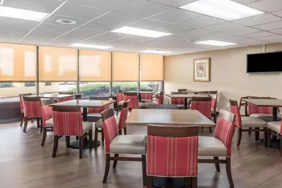 a restaurant with tables and chairs and a flat screen tv at Comfort Inn & Suites Piqua-Near Troy-I75 in Piqua