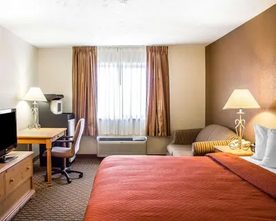 a hotel room with a bedroom with a bed and a desk at Quality Inn Elyria in Elyria