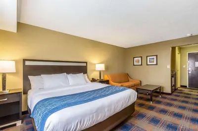 a hotel room with a large bed and a chair at Comfort Inn Independence - Cleveland in Independence