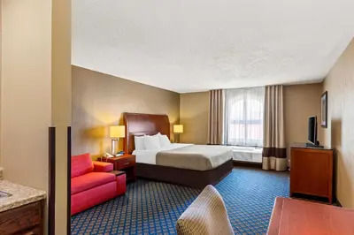 a hotel room with a bed and a red couch at Quality Inn & Suites Seville in Seville
