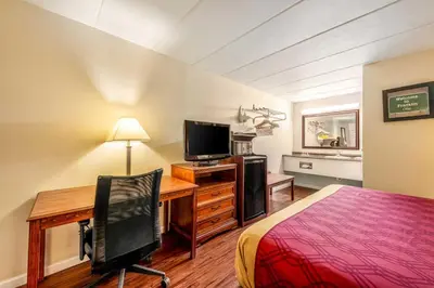 a hotel room with a desk and a bed and a television at Econo Lodge Franklin - Springboro in Franklin