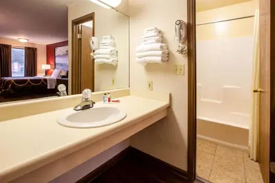 a bathroom with a sink and a mirror and a tub at Super 8 by Wyndham Sandusky in Sandusky