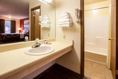 a bathroom with a sink and a mirror and a tub at Super 8 by Wyndham Sandusky in Sandusky