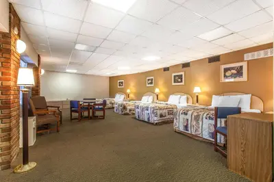 a hotel room with four beds and a table and chairs at Rodeway Inn Sandusky North in Sandusky