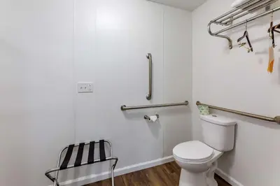 a white bathroom with a toilet and a chair at Econo Lodge Inn & Suites Sandusky South in Sandusky