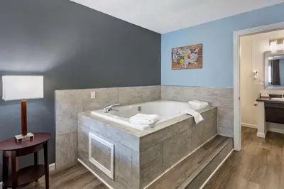 a bathroom with a tub with a table and a lamp at Econo Lodge Inn & Suites Sandusky South in Sandusky