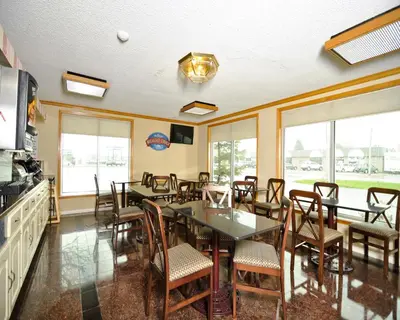 a dining room with tables and chairs and windows at Baymont by Wyndham Sandusky in Sandusky